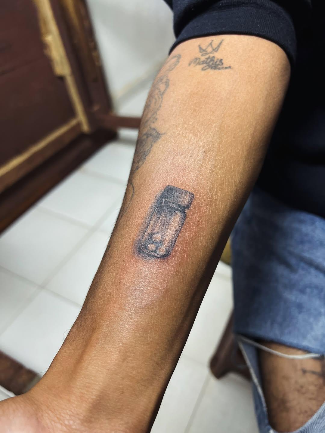 Tatouage minimaliste d’un flacon réalisé par Kaopy Gasy